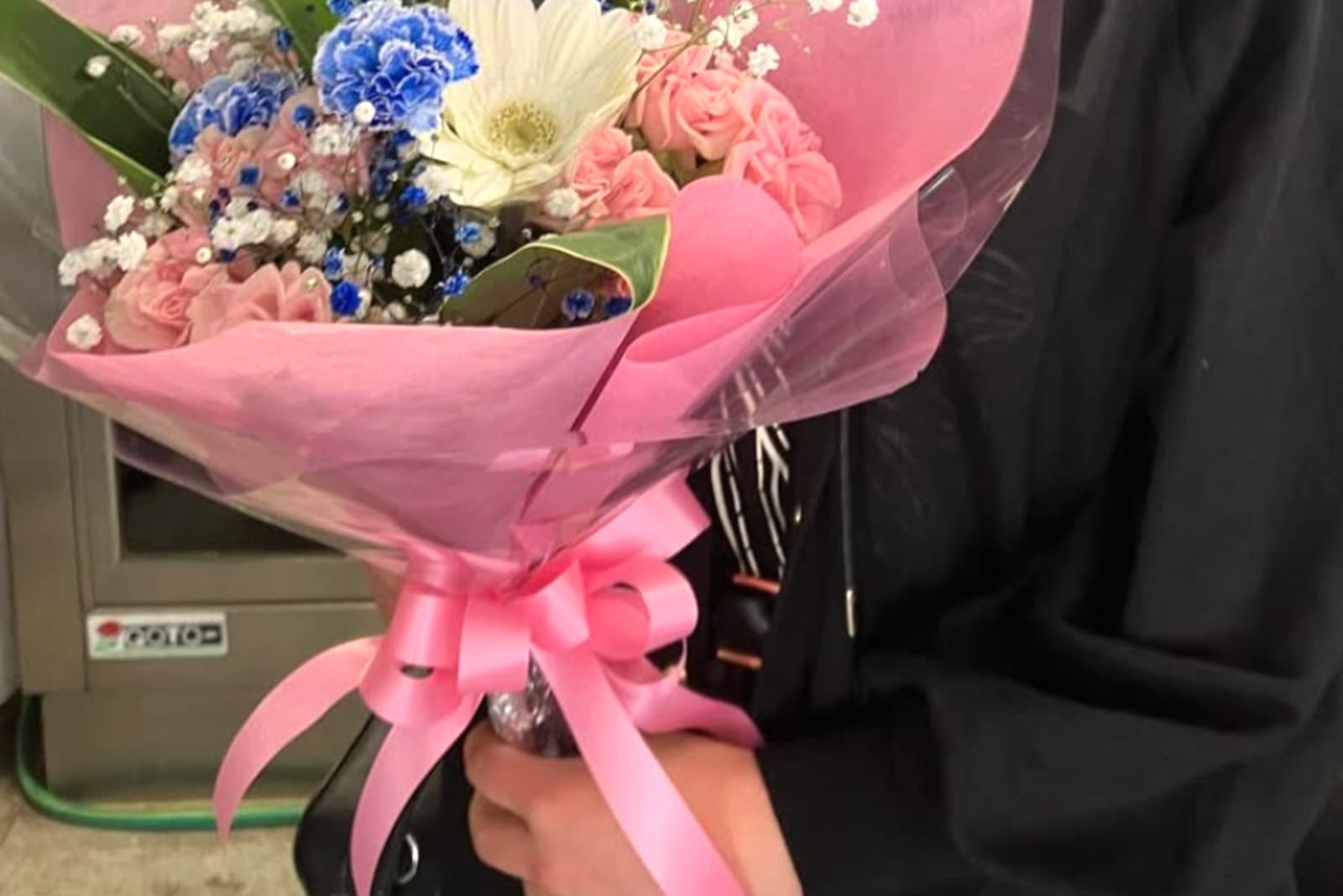 店内で仕立てたピンクの花束を手渡すようす